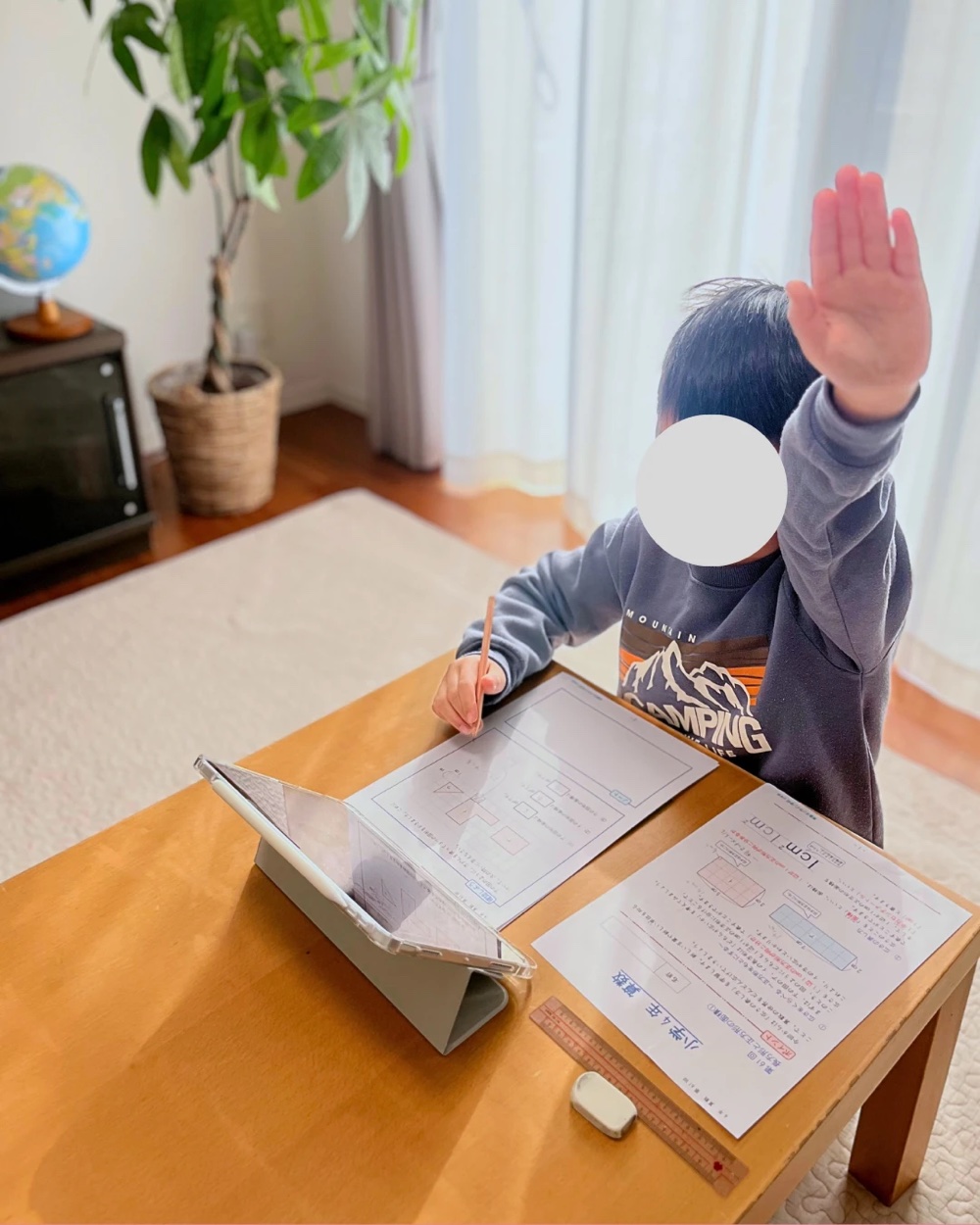 授業の問いかけに手を挙げる小学生
