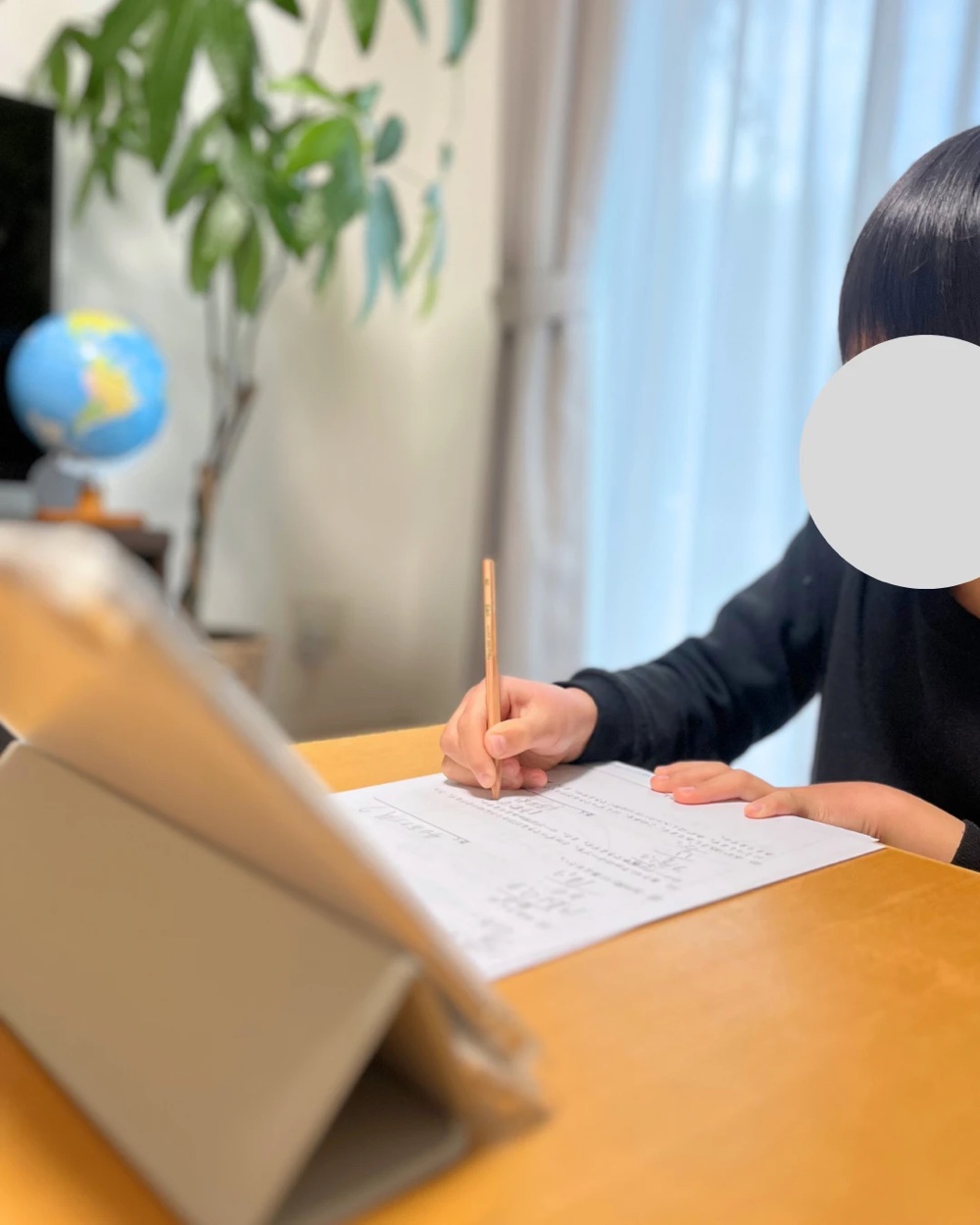 プリントに手で書いて問題を解く小学生